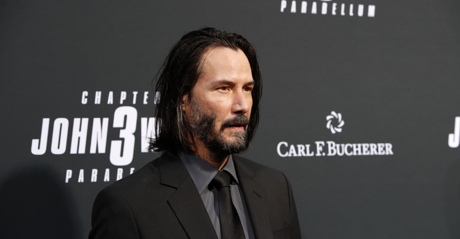 Keanu Reeves kneels on stage as adoring fans refuse to stop standing ovation
